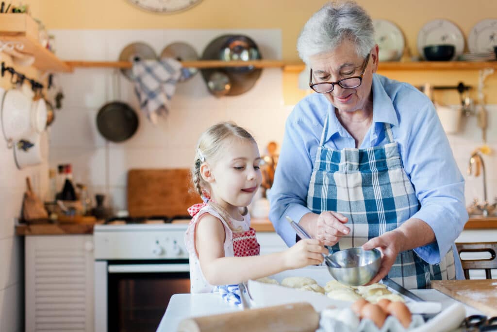 Farmor bakar bröd med sitt barnbarn i köket.